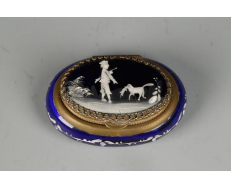 A VICTORIAN 'BRISTOL' BLUE SNUFF BOX, the oval lid decorated in white enamels with a huntsman and dog, within a gilt metal mo