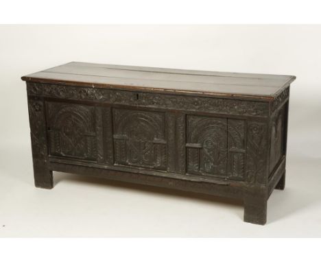 A JAMES I OAK COFFER, with a broad rectangular top with moulded border above a three panel front with arcaded panels and cent