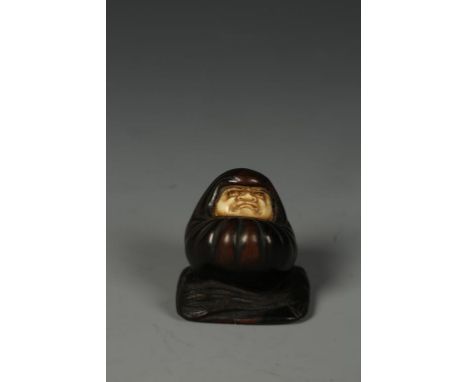 A JAPANESE WOOD AND IVORY DARUMA NETSUKE, the crouching figure looking upwards and on a square base with a fly whisk, Meiji, 