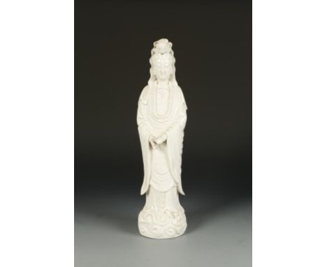 A CHINESE LARGE BLANC-DE-CHINE GUANYIN FIGURE, the deity standing and wearing flowing gowns, on a cloud scroll base, Qing, 18