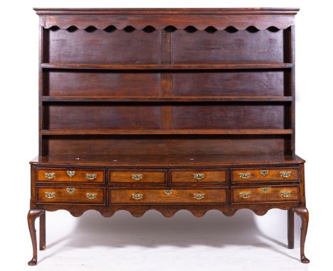 A George III and later oak dresser, matched three-shelf rack under a moulded canopy, the base with a configuration of seven d