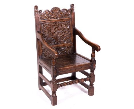 A joined oak chair, late 17th Century and later, shaped cresting with stylised leaves and acorns, the back panel emblematic o