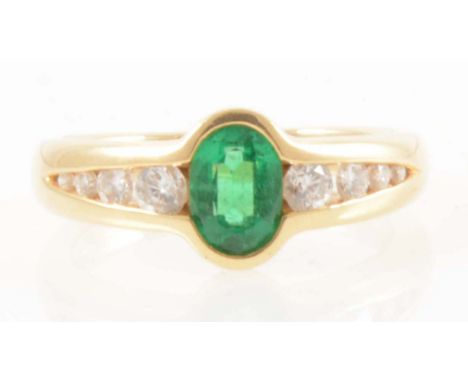 An 18 carat yellow gold ring set with an emerald and eight diamonds, the oval mixed cut emerald 7mm x 5mm set in an 18 carat 