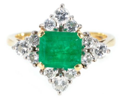 An emerald and diamond cluster ring, the rectangular step cut emerald 7mm x 6mm x 3.2mm, claw set horizontally with three bri