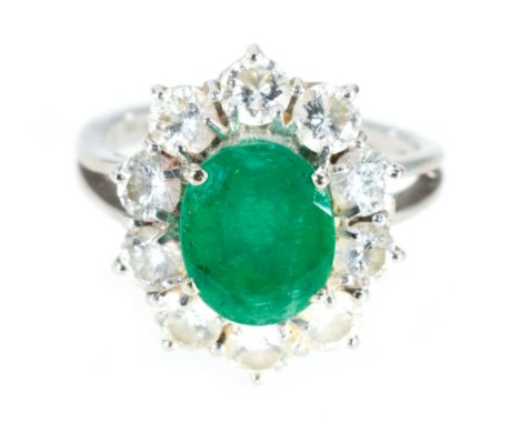 An emerald and diamond oval cluster ring, the oval mixed cut emerald 9mm x 7.5mm, claw set and surrounded by ten brilliant cu