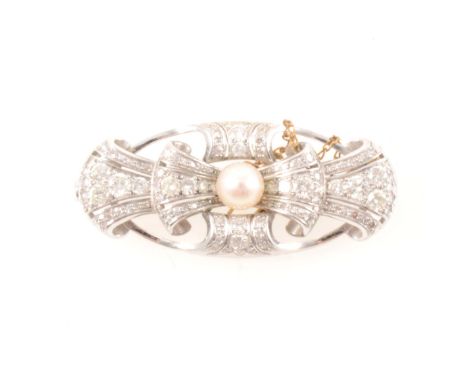 A diamond and pearl brooch, the white metal oval frame holding a diamond set bow and having a 7mm pearl to the centre, ninety