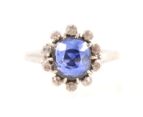 A sapphire and diamond cluster ring, an oval mixed cut sapphire 8.6mm x 7.4mm x 5.6mm, claw set and surrounded by ten old cut