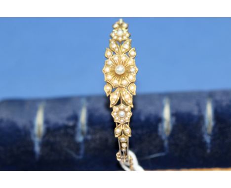 An unmarked gold and seed pearl hinged bangle.   Condition Report:  Good overall.  Clasp and hinge firm.  All pearls present 