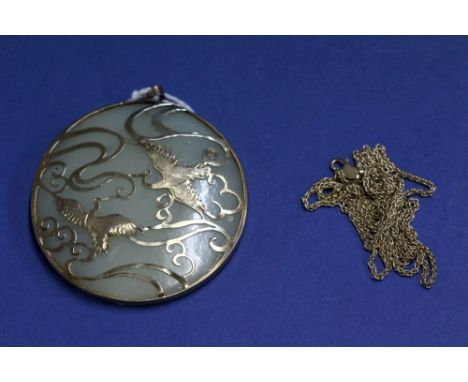 A large mutton fat jade pendant in a metal mount decorated flying cranes; together with a 9ct gold chain, 5.8g.