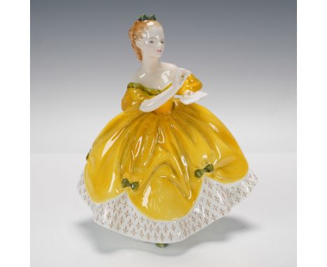 A figure of a young lady in a yellow and white gown with green accents. She is holding a journal and pencil. Royal Doulton ba