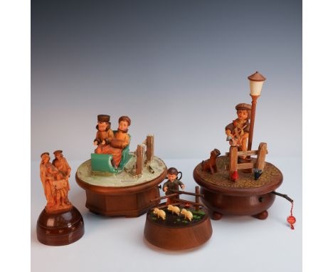 Set of four music boxes, three marked Anri. Each features intricately detailed figures in charming rustic and winter scenes, 