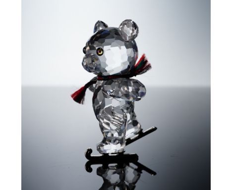 This charming Swarovski Kris Bear figurine captures the joyful spirit of winter, featuring a clear faceted crystal bear weari