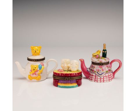 A whimsical trio of hand-painted porcelain hinged treasure boxes, including a white teapot with a cheerful teddy bear and bal