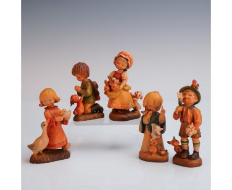 A delightful group of five hand carved and painted Anri wooden figurines, each featuring a child in the company of beloved an