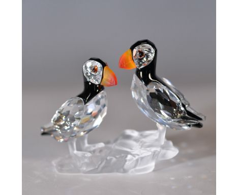 A stunning Swarovski crystal figurine depicting two puffins perched on an ice-like base. This intricately designed piece feat