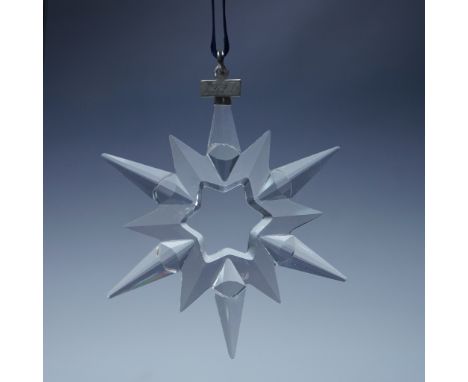 This Swarovski 1997 Annual Christmas Ornament is a stunning, multifaceted crystal star with a hollowed-out center in the shap