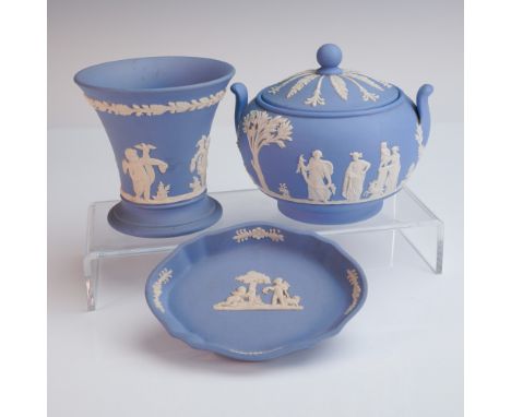 A three-piece collection of classic Wedgwood jasperware in blue, featuring a covered sugar bowl, trumpet-form vase, and a sca
