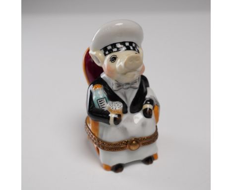 Charming hand-painted Limoges porcelain trinket box in the form of a pig waiter seated in a red-backed chair. Dressed in form