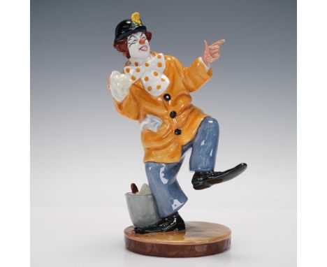Part of the Clowns collection. Clown in a yellow jacket, blue pants, and polka dot tie, holding a pie. Royal Doulton backstam