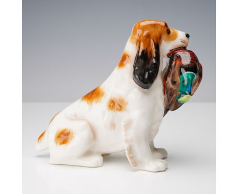 A finely modeled porcelain figurine in the style of Royal Doulton, depicting a spaniel seated with a captured pheasant gently