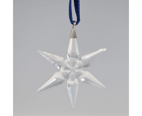Swarovski crystal ornament featuring a faceted eight-point star design, suspended from a blue ribbon, accompanied by its orig
