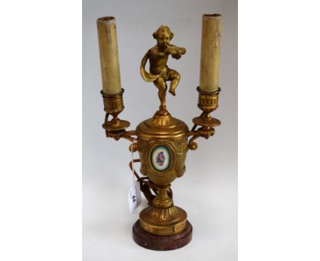 A 19th century French gilt two branch urnular table lamp, cherub finial, inset with oval enamel plaque decorated with flowers