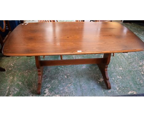 An Ercol elm trestle type dining table, rounded rectangular top, vasular shaped end supports, rectangular stretcher, 152cm lo