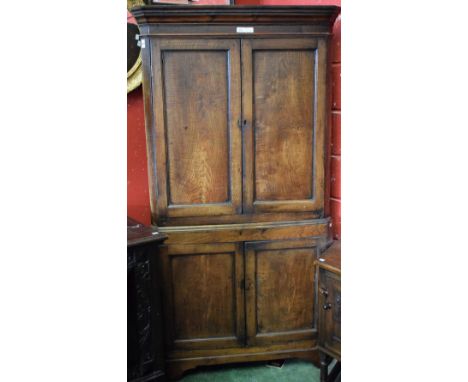 A 19th century elm floor standing corner cupboard, outswept cornice above a pair of panel doors enclosing two shaped shelves,