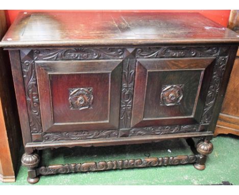 A Jacobean style oak side table, hinged rectangular top above a pair of cupboard doors enclosing a shelf, 123cm wide