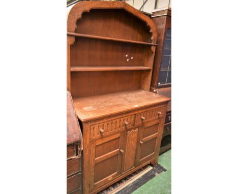 A 20th century oak Welsh type dresser, arched apron above two plate racks, the base with two short drawers above a pair of cu