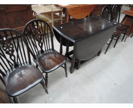 A traditional dark stained gate leg dining table and set of 4 spindle and wheelback chairs