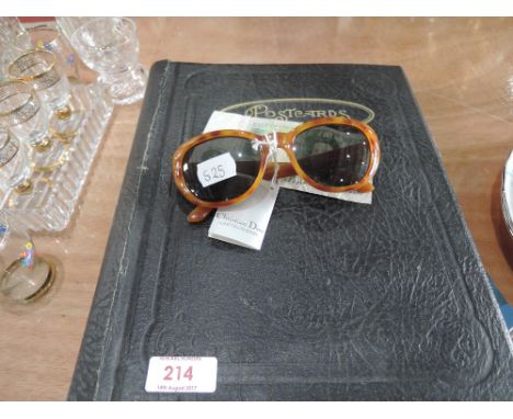 A pair of Christian Dior sunglasses, one pound note and vintage postcard album