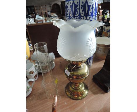 A vintage brass oil lamp with decorative shade