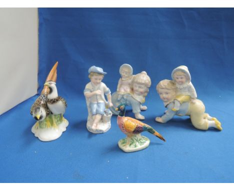 A pair of continental ceramic piano babies with young child on there backs, a similar figure of a boy with flowers and a pair