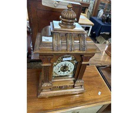 A late 19th Century mantel clock set in an architectural carved wooden case, fitted with a brass movement striking on a coile