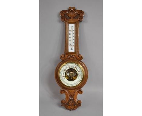 A Late 19th Century Aneroid Barometer with a Glass Thermometer in a Carved Oak Case, 54cms High 