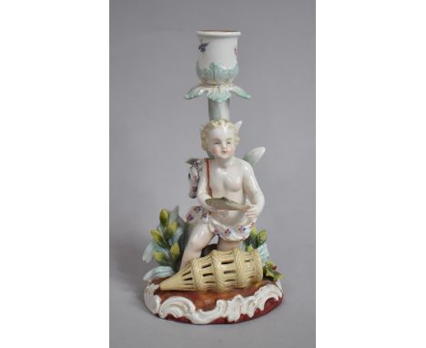 A Continental Porcelain Figural Candlestick in the Form of a Cherub with Fish Trap, Under Glaze R Make to Base. 19cms High