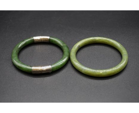 A Chinese jade hinged bangle having metal mounts, 8cm; together with another jade bangle 7.9cm. (2) 