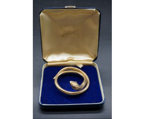 A 9ct gold articulated snake bangle with ruby set eyes, gross weight&nbsp;21g including steel inner spring. 
