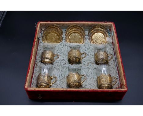 A cased set of six Turkish gilt metal coffee glass holders and saucers,&nbsp;(lacking two glasses). 