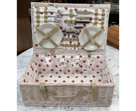 A Wicker hamper with a setting for four including plates, cutlery and glasses
