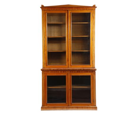 An early 19th century satinwood bookcase cabinet, inlaid with ebonised stringing, the detachable classical pediment above a p