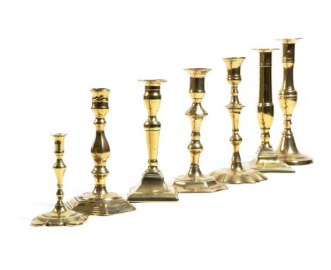 A small collection of brass candlesticks, including: a George II taperstick, an early 19th century candlestick with a push-up