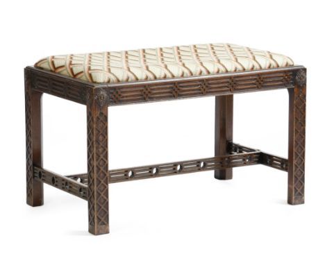 A mahogany stool in Chinese Chippendale style, with a lattice needlework drop-in seat, above a fret carved frieze and legs un