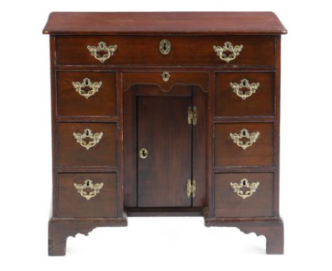 A George II fruitwood kneehole desk, the top with a caddy moulded edge, above eight drawers around a central cupboard, on bra