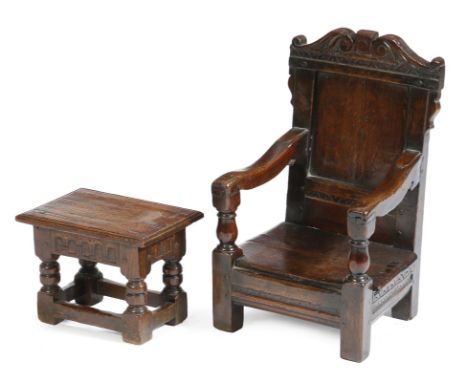 An oak child's panelled back armchair, with a scroll carved top rail, above a solid seat, possibly 17th century, 57.3cm high,