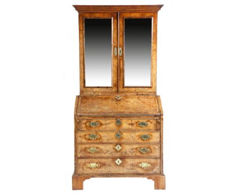 A George I walnut and burr walnut bureau cabinet, cross and feather banded, the moulded cornice above a pair of mirrored door