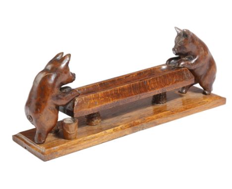 A treen pen tray, in the form of two pigs feeding at a trough, on an oak plinth, late 19th / early 20th century, 39.5cm long.