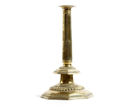 A large late 17th century sheet brass candlestick, repoussé decorated, with a fluted nozzle, above an octagonal stop fluted s
