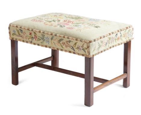 A mahogany stool in George III style, with a petit-point floral needlework seat, on chamfered and moulded legs united by an '